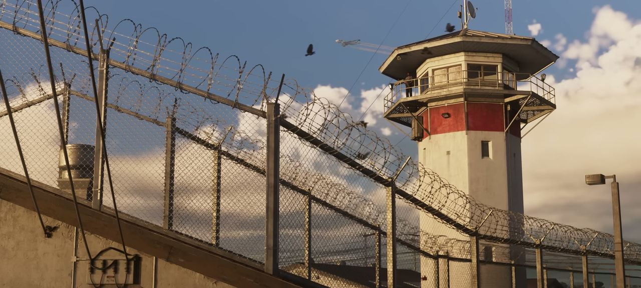 A prison watchtower behind razor wire.